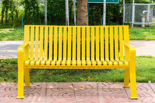 Colored yellow bench in a park outdoor garden