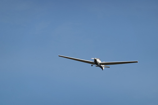 Small white plane with blue stripes of a cessna propeller flying in a clear sky before landing on Sabadell Airport