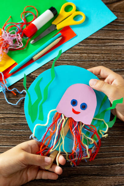 istock Summer puppet stics toy octopus on a wooden table. Handmade. Childrens creativity project, crafts for kids. 1316006640