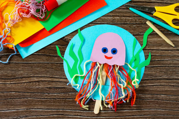 istock Summer puppet stics toy octopus on a wooden table. Handmade. Childrens creativity project, crafts for kids. 1316006641