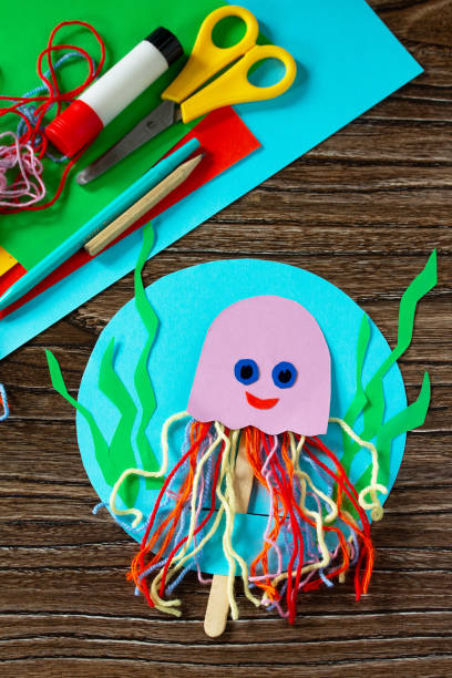 istock Summer puppet stics toy octopus on a wooden table. Handmade. Childrens creativity project, crafts for kids. 1316006645