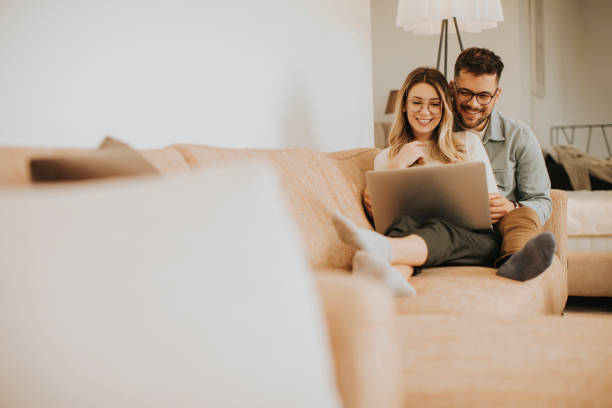 istock Young couple using laptop together while sitting on sofa at home 1316007477
