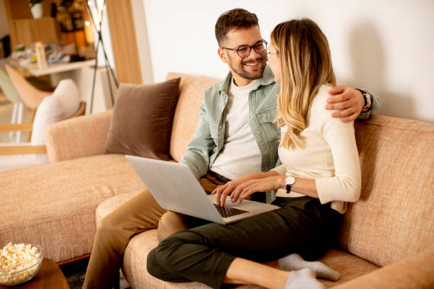 istock Young couple using laptop together while sitting on sofa at home 1316007517