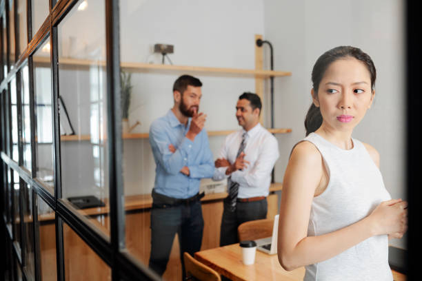 Businesswoman eavesdropping on conversation Serious young businesswoman eavesdropping on conversation of her male colleagues in meeting room eavesdropping stock pictures, royalty-free photos & images