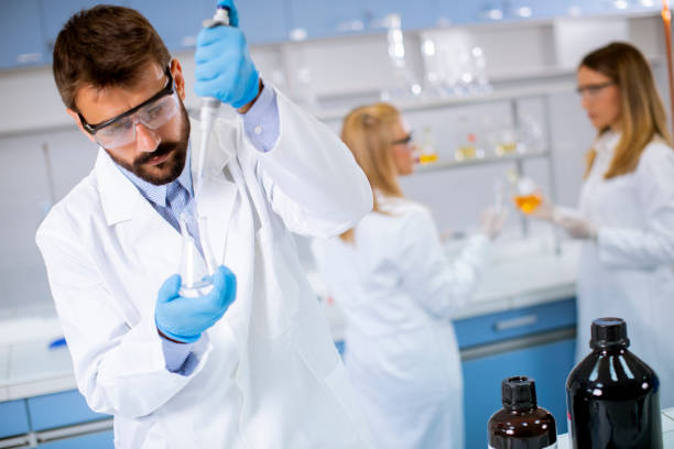 istock Young researcher in protective workwear standing in the laboratory and analyzing flask with liquid 1316008655