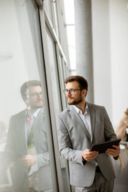 istock Young businessman standing with digital tablet by the office window 1316008693