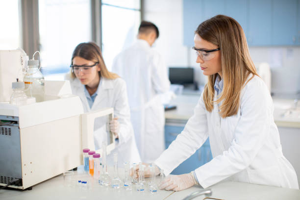 Female scientists in a white lab coat putting vial with a sample for an analysis on a ionchromatography system in biomedical lab Young female scientists in a white lab coat putting vial with a sample for an analysis on a ionchromatography system in biomedical lab quantitative research stock pictures, royalty-free photos & images