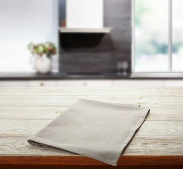 Photo of Empty white table cloth on wooden desk. Kitchen background.