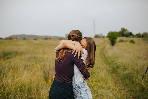 Two cheerful young female friends hugging in beautiful spring nature