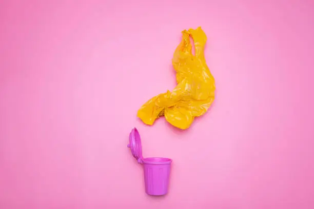 Photo of Yellow wrinkled plastic bag is about to fall into pink trash