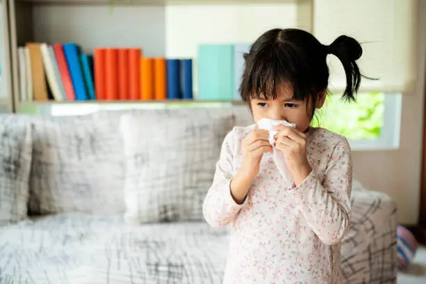 Runny nose. Sick little girl blowing her nose and covering it with handkerchief
