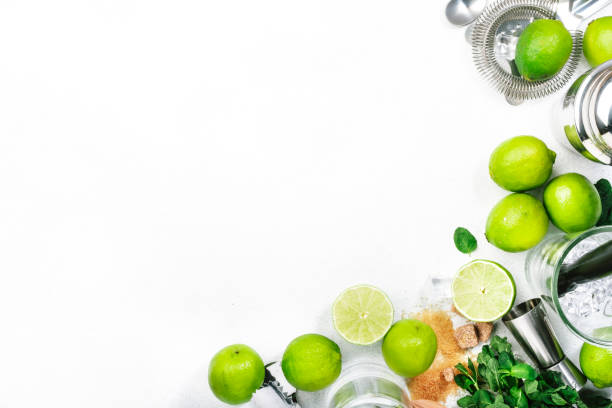 istock Mojito cocktail preparing ingredients: lime, mint, ice and bar tools, white background, top view 1316020231