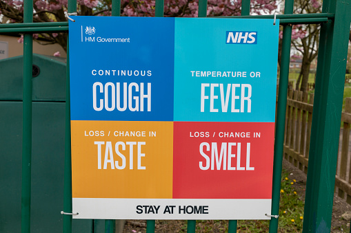 Sheffield, South Yorkshire, England - May 1 2021: A sign from the NHS and HM Government advising people to stay at home if they have a cough, fever or have lost their sense of taste and smell amid the COVID-19 pandemic.