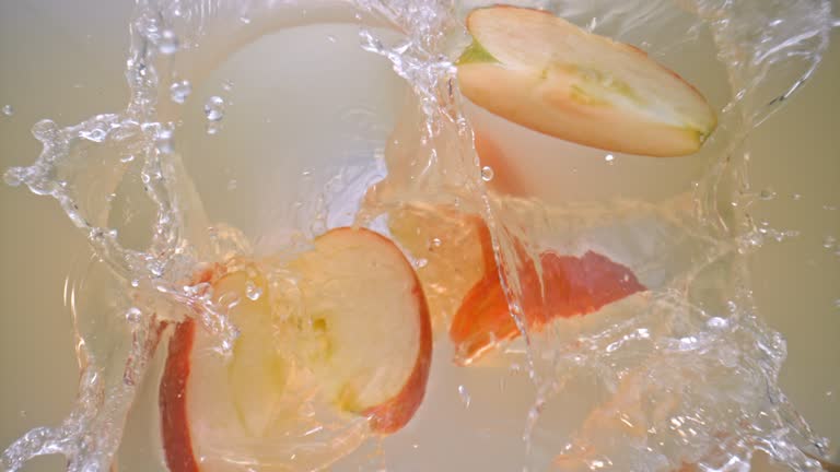 SLO MO LD Red apple wedges falling into apple juice