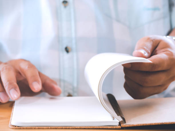 istock Male student or businessman opening note book to finding information and sitting at assignment in university library or workplace. 1316021386