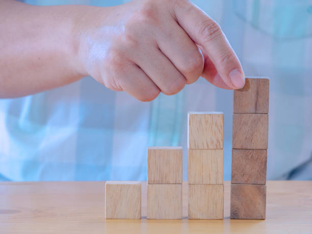istock Hand arranging wood cube stacking as stair step shape on wooden table .Business concept create symbol or logo, development, growth and management concept. 1316021391
