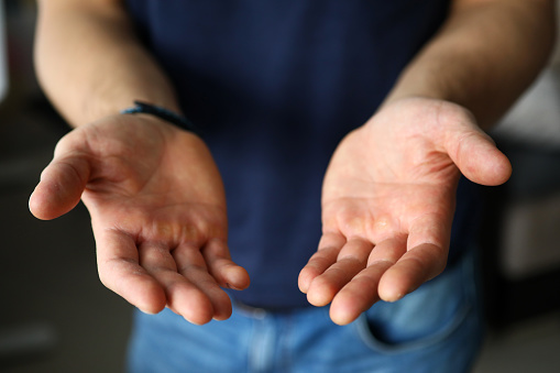 Man stretching empty hands with palms up to camera close-up