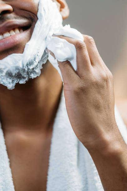 hombre africano cuidado de la piel masculino aplicando espuma de afeitar - male towel men human face fotografías e imágenes de stock