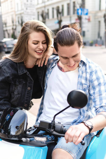 couples élégants ayant l’amusement tout en conduisant le scooter électrique sur la rue de ville - motorcycle motor scooter couple young adult photos et images de collection