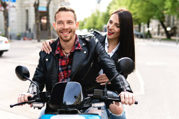 couples élégants ayant l’amusement tout en conduisant le scooter électrique sur la rue de ville - motorcycle motor scooter couple young adult photos et images de collection