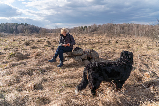 Woman and dog are resting together during a hike in the springtime.