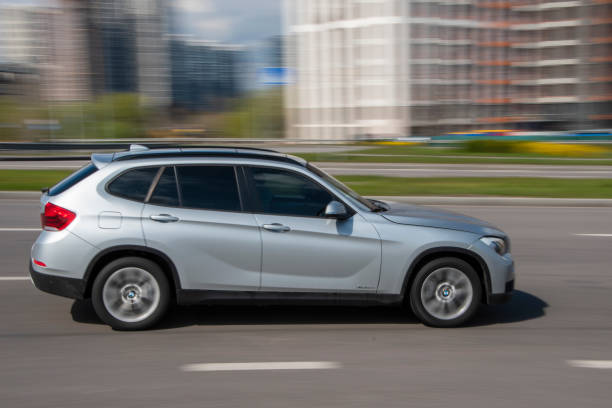 silber bmw x1 auto bewegt sich auf der straße. - bell stock-fotos und bilder