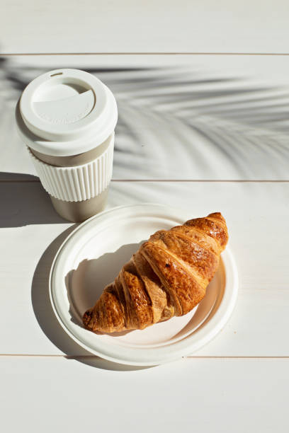 istock Hot coffee on the go and croissants for breakfast. Biodegradable, reusable takeaway cup 1316029545