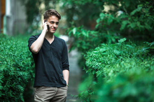 Charming young man talking on mobile phone outdoors.