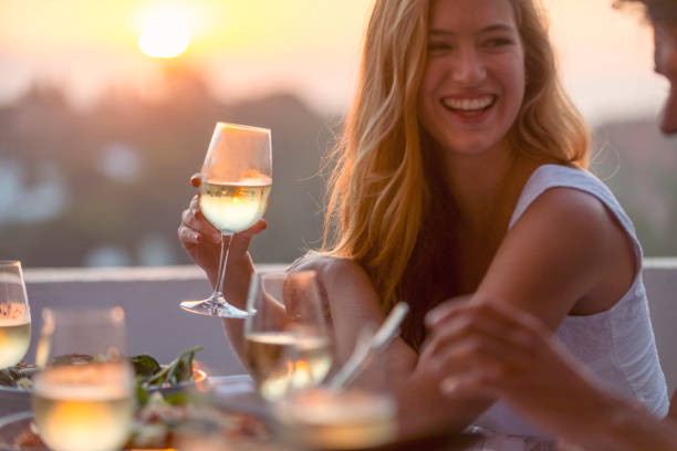 przyjaciele rozmawiający i pijący na kolacji z kieliszkami do wina na stole - couple dinner summer sunlight zdjęcia i obrazy z banku zdjęć