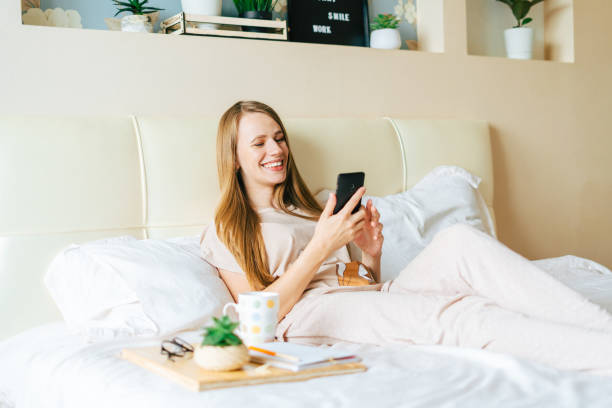 istock Young woman taking a selfie on smartphone while sitting on bed 1316031278