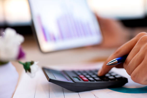 close up of man checking on incomes, using calculator - incomes imagens e fotografias de stock