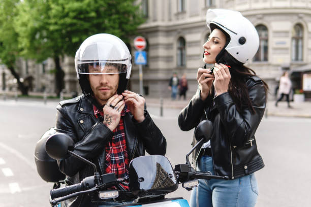 couples élégants utilisant des casques de moto avant de monter sur le scooter électrique - motorcycle motor scooter couple young adult photos et images de collection