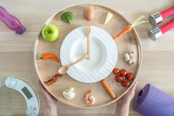 istock Intermittent fasting IF diet concept with 16:8 hour clock timer for skipping meal and eating keto low carb, high fat food meal healthy nutritional dish with gym exercise for body weight loss 1316032279