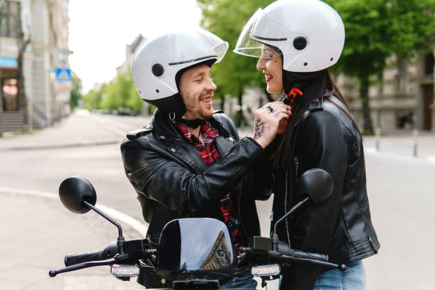 couples élégants utilisant des casques de moto avant de monter sur le scooter électrique - motorcycle motor scooter couple young adult photos et images de collection