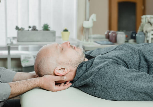 lekarz cst używa delikatnego nacisku w celu złagodzenia stresu i bólu spowodowanego kompresją, leczeniem krzyżowym czaszkowym, osteopatią i terapią manualną - head massage headache massaging alternative therapy zdjęcia i obrazy z banku zdjęć