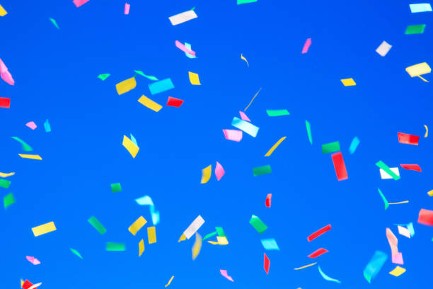 istock multicolored confetti on clear blue sky background. Concept of h 1316036721