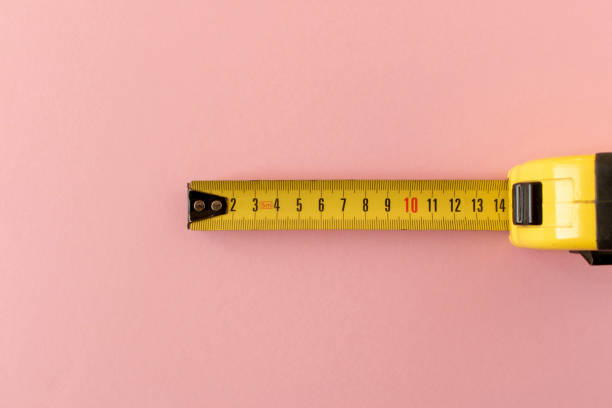 istock Yellow measuring tape on a pink background. Close-up. 1316040417