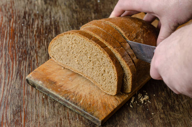 istock Hands slice bread on a wooden cutting board. 1316040823