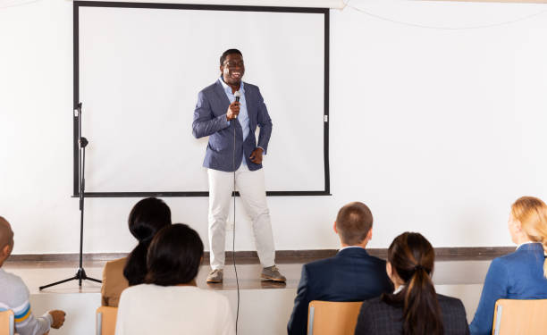 istock Expressive african american speaker with microphone on conference room stage 1316041875