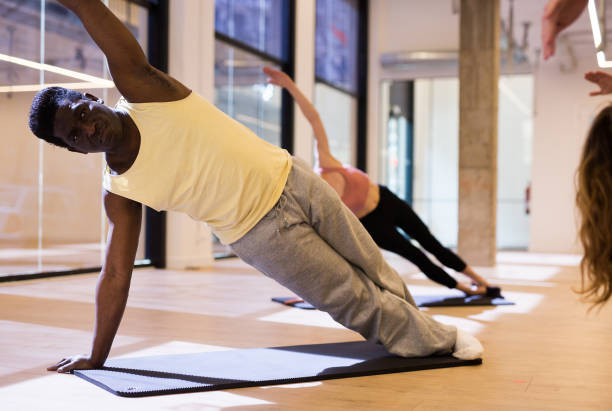 istock Aframerican man doing pilates workout with group at gym 1316042250