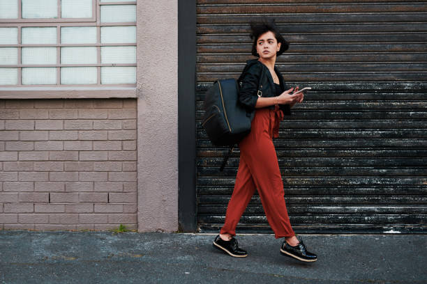 istock Shot of a young woman looking back while using her mobile phone and walking past a garage door in the city 1316043085