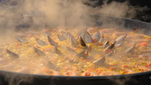 Slow motion: chef cooking paella with shrimp, mussel - close up