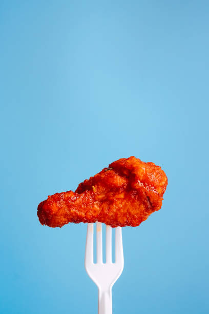 istock Korean style fried chicken on plastic fork with blue background, fast food Concept. 1316047807