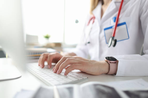 istock Doctor sitting at table and typing on computer keyboard closeup 1316048214