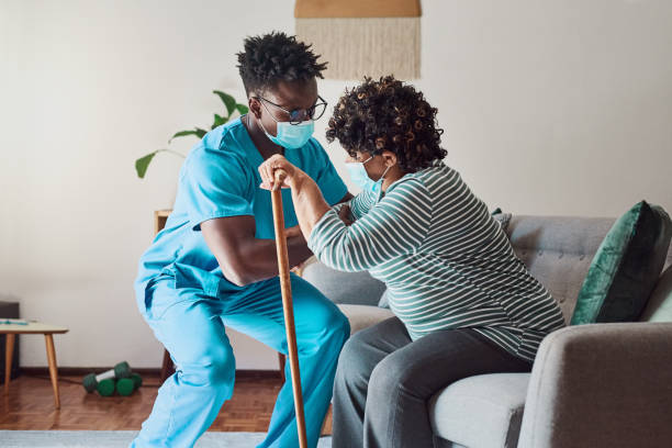 Shot of a young male nurse helping an elderly patient stand stock photo