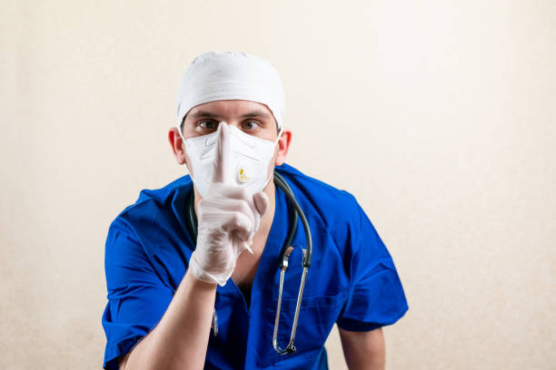 Doctor in blue uniform and medical mask. Shows quietly. stock photo