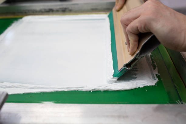 istock Serigraphy silk screen print process at clothes factory. Frame, squeegee and plastisol color paints 1316050354