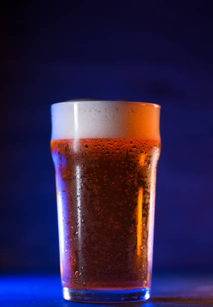 istock A glass of craft light beer on a dark background, colored trend light 1316051489