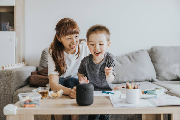 Young boy excited about smart speaker Mother and son at home, communicating with smart speaker. smart home family stock pictures, royalty-free photos & images