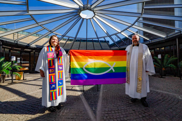 Stockholm, Sweden Stockholm, Sweden April 25, 2021 Two priests in the Swedish Church pose with a rainbow LGTBQ flag to promote diversity within the church. clergy stock pictures, royalty-free photos & images